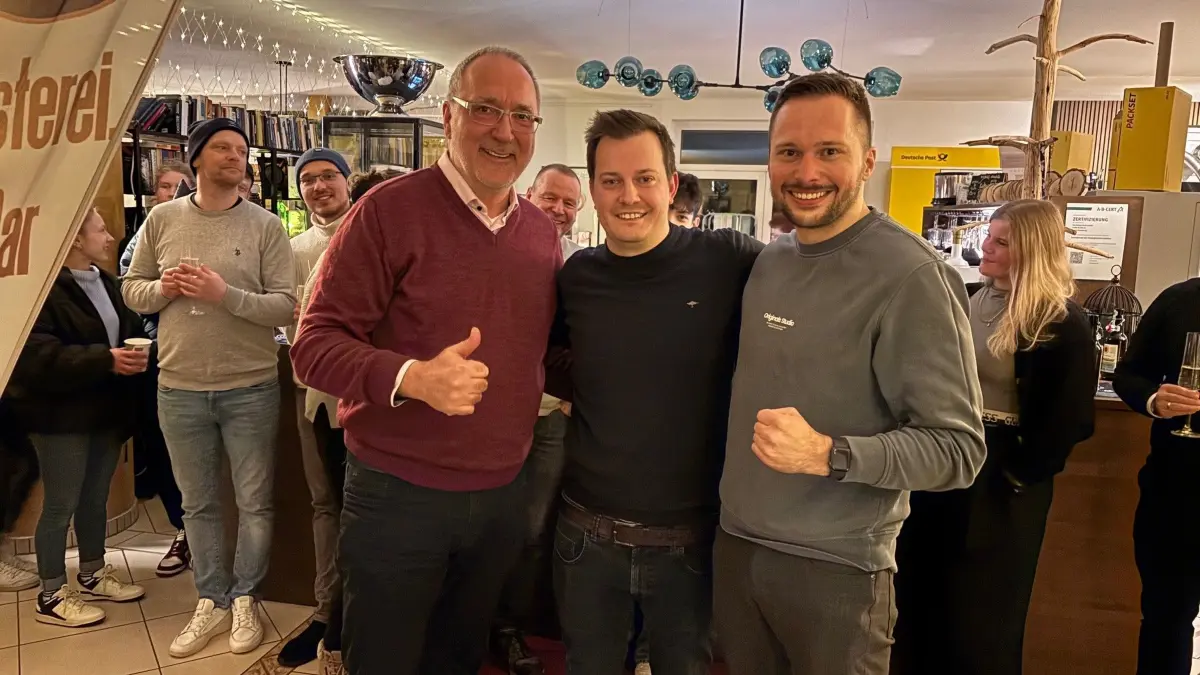 Strahlender Gewinner in der Mitte: Dem parteilos angetretenen Patrick Hübner gratulieren Strausbergs Ex-Bürgermeister Hans Peter Thierfeld (links) und der Stadtverordnete Florian Grube sowie zahlreiche Unterstützer in seiner Kaffeerösterei.