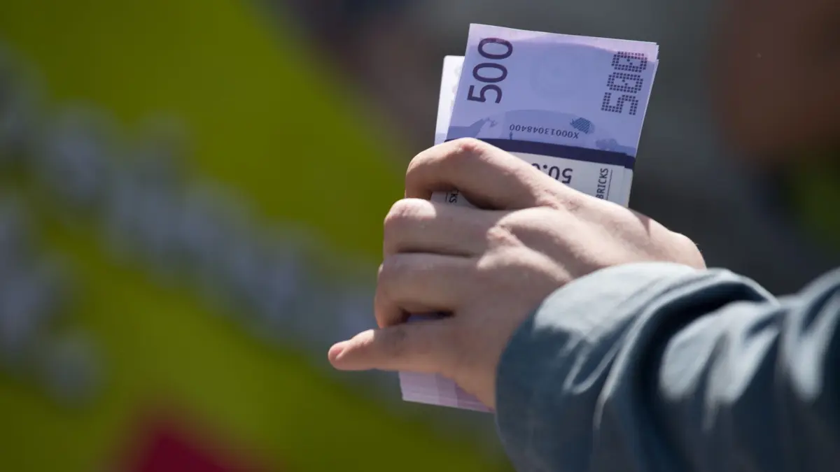 Ein Mann hält ein Bündel mit Spielgeld in der Hand