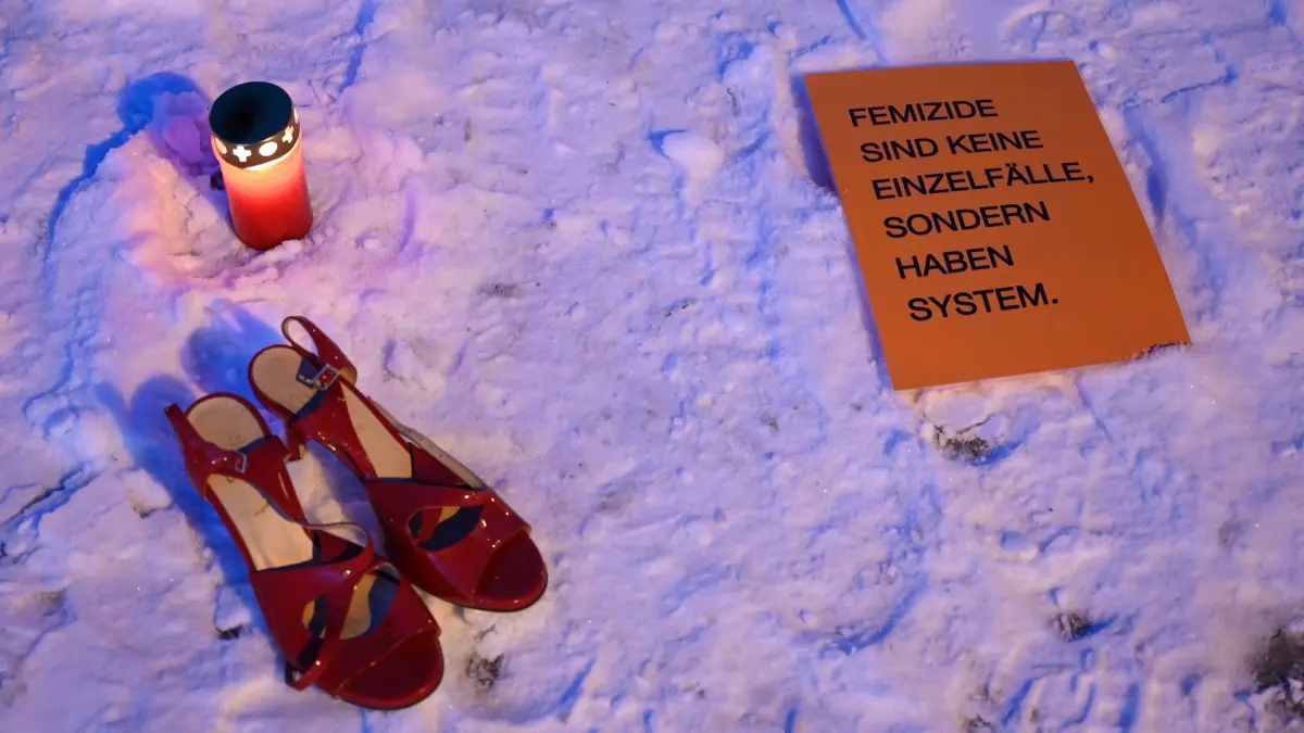 Gedenkkundgebung für getötete 18-Jährige in Hamburg: 18.02.2026, Hamburg: Ein Schild mit der Aufschrift „Femizide sind keine Einzelfälle, sondern haben System.“ liegt während einer Gedenkkundgebung des Anti-Femizid-Netzwerks-Hamburg für die getötete 18-Jährige am U-Bahnhof Wandsbek neben Damenschuhen und einer Kerze. Ein 25-jähriger Mann hatte eine 18-jährige Frau mit sich ins Gleisbett vor einen Zug der Linie U1 gezerrt. Beide Menschen kamen ums Leben Foto: Daniel Bockwoldt/dpa +++ dpa-Bildfunk +++
