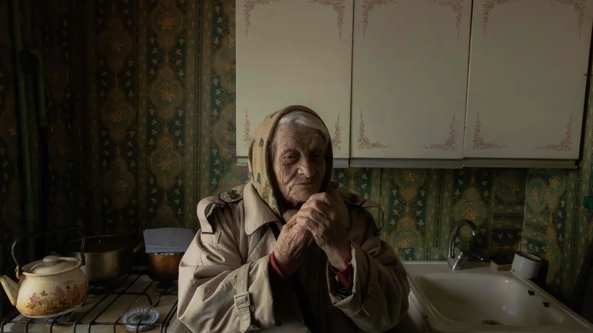 (FILES) Yevheniia Yeremina, an 89-year-old pensioner, stands in her kitchen using a gas stove to warm her apartment, which has no electricity and heating, in Kyiv on January 26, 2026, following missile and drone attacks on Ukrainian energy infrastructure amid the Russian invasion in Ukraine. Russia has this month stepped up its strikes against Ukraine's power and heating infrastructure, plunging Kyiv residents into darkness and cold as temperatures dropped as low as -20C. (Photo by Roman PILIPEY / AFP)