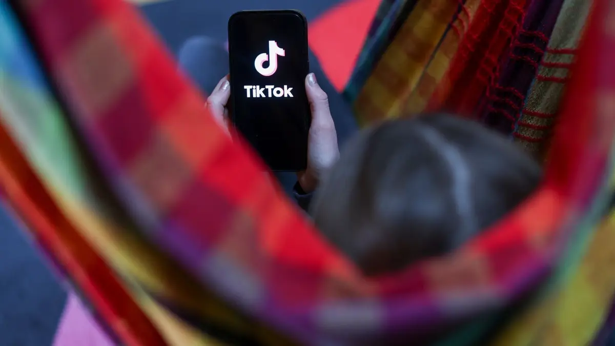 Videoplattform TikTok: ILLUSTRATION - 17.02.2026, Sachsen, Leipzig: Ein Mädchen hält ein iPhone 16 in den Händen, auf dessen Display das Logo der Video-Plattform TikTok zu sehen ist. (zu dpa: «Kommt eine Social-Media-Altersgrenze ab 14 Jahren?») Foto: Jan Woitas/dpa +++ dpa-Bildfunk +++