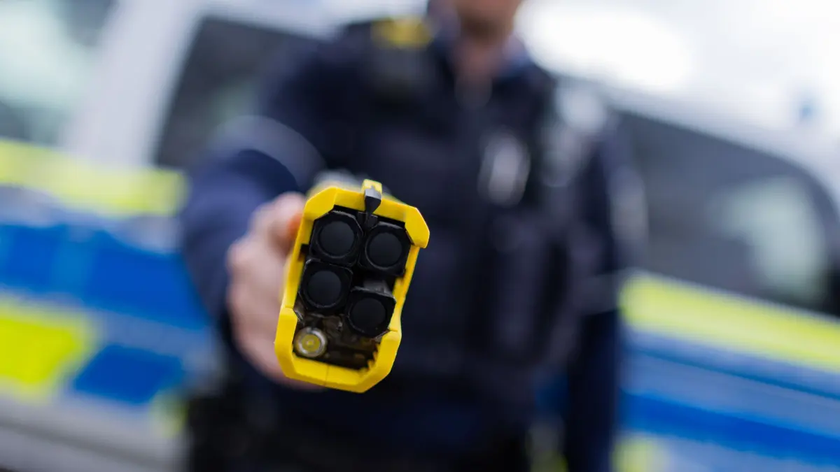 Kabinett beschließt Polizeigesetz: ARCHIV - 07.03.2024, Nordrhein-Westfalen, Düsseldorf: Ein Polizist hält einen Taser (Distanzelektroimpulsgerät) in den Händen. Das Gerät sendet nach Abschuss zweier Elektroden Stromimpulse ab. (zu dpa: «Kabinett beschließt Entwurf für neues Polizeigesetz») Foto: Rolf Vennenbernd/dpa +++ dpa-Bildfunk +++