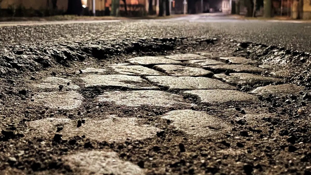 Landesstraße L20 in Velten, Rosa-Luxemburg-Straße, an der Schranke Bahngleise, Schlagloch, Schlaglöcher, schlechter Zustand Straße, fotografiert nachts