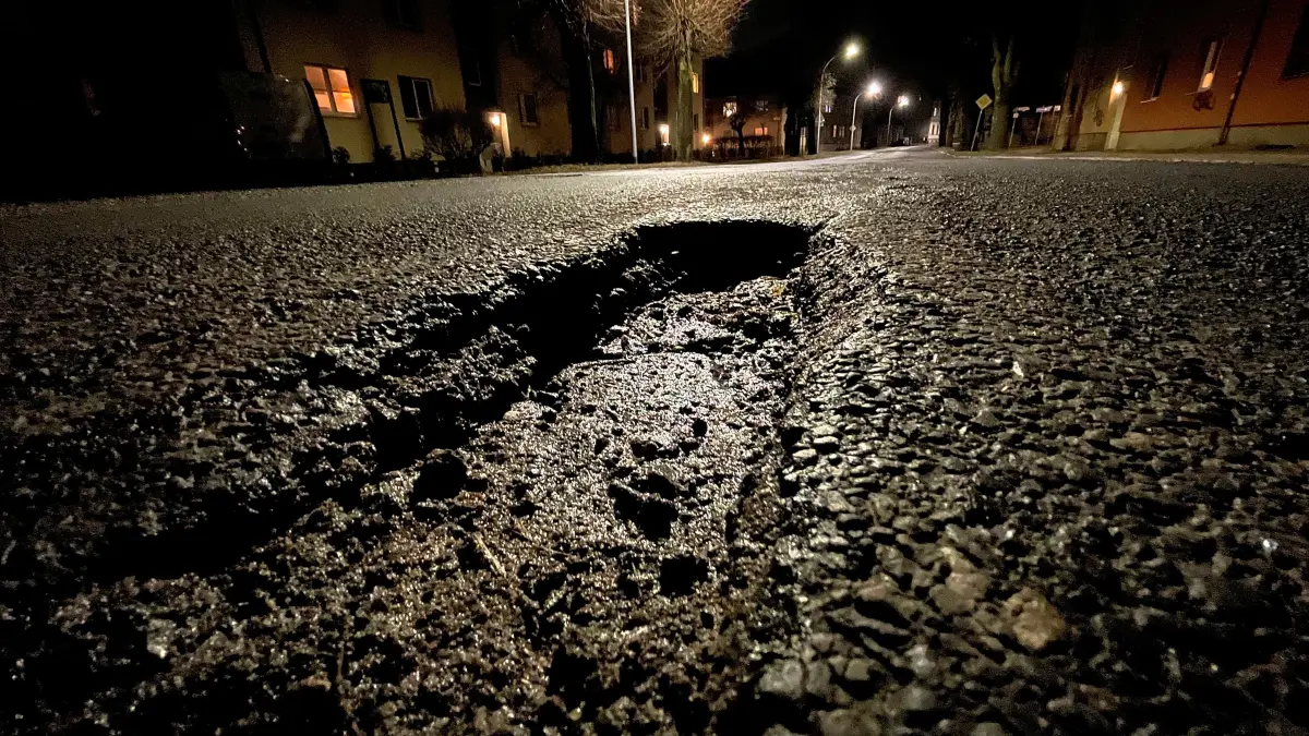 Landesstraße L20 in Velten, Rosa-Luxemburg-Straße, an der Schranke Bahngleise, Schlagloch, Schlaglöcher, schlechter Zustand Straße, fotografiert nachts