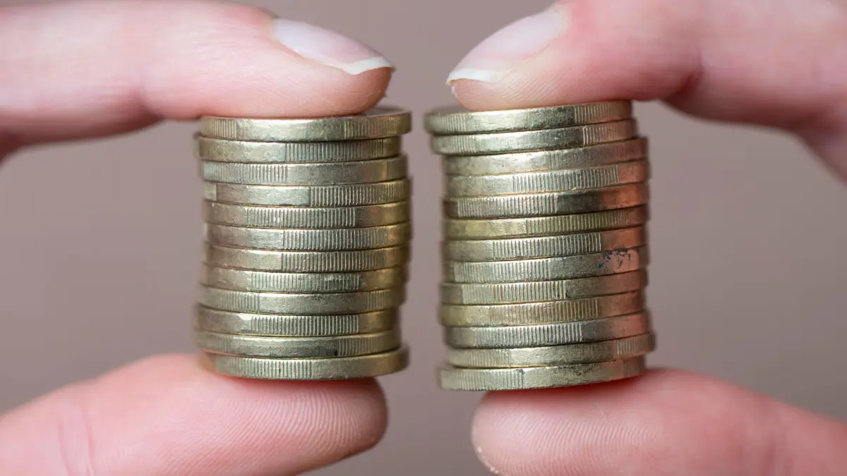 Gender-Pay-Gap: ILLUSTRATION - 05.03.2025, Sachsen, Dresden: Eine Frau hält gestapelte Euro-Münzen zwischen Daumen und Zeigefinger. (zu dpa: «Gender Pay Gap in Hamburg sinkt nur minimal auf 17 Prozent») Foto: Sebastian Kahnert/dpa +++ dpa-Bildfunk +++