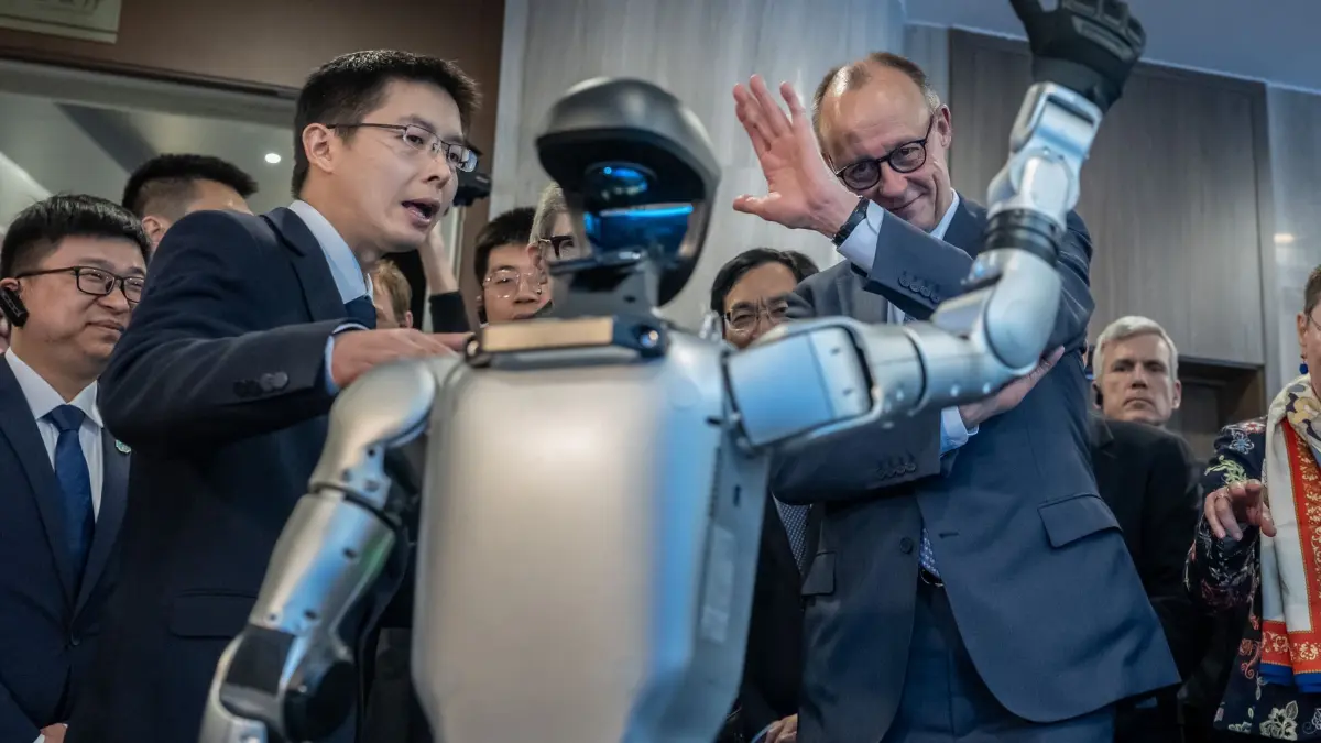 Bundeskanzler Merz besucht China: 26.02.2026, China, Hangzhou: Bundeskanzler Friedrich Merz (CDU) besucht die Firma Unitree Robotics in der Provinz Zhejiang und lässt sich von Gründer und Geschäftsführer Wang Xingxing (l) durch die Präsentationsräume führen. Die Firma ist für ihre humanoiden Roboter bekannt. Foto: Michael Kappeler/dpa +++ dpa-Bildfunk +++