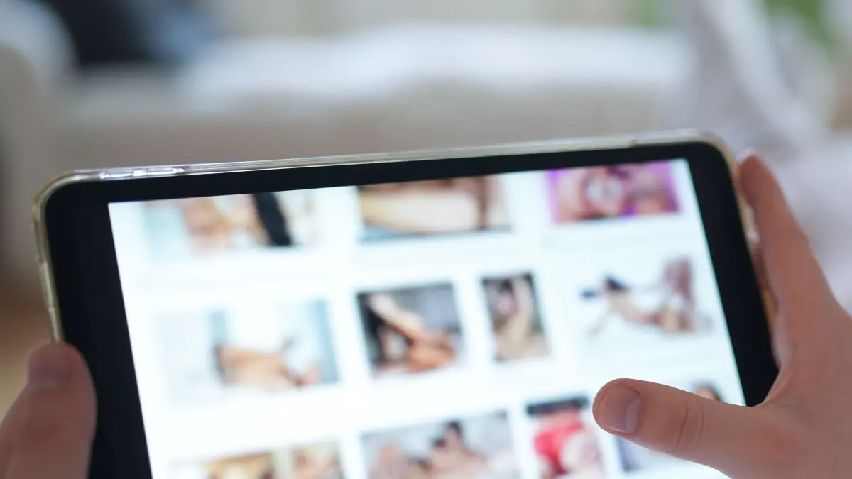 ILLUSTRATION - Ein junger Mann schaut sich auf einem Smartphone eine Porno-Internetseite an (gestellte Szene). (zu dpa: «Ermittlung wegen Kinderpornografie - Einsatz im Raum Dresden») +++ dpa-Bildfunk +++