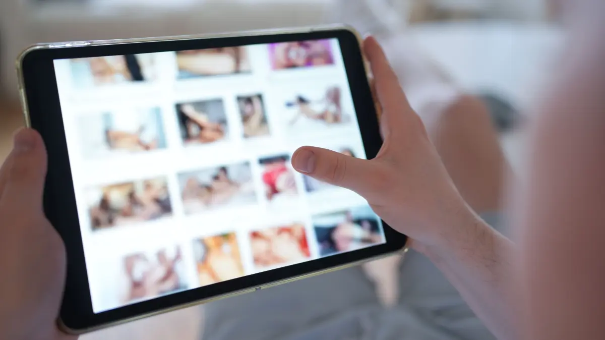 ILLUSTRATION - Ein junger Mann schaut sich auf einem Smartphone eine Porno-Internetseite an (gestellte Szene). (zu dpa: «Ermittlung wegen Kinderpornografie - Einsatz im Raum Dresden») +++ dpa-Bildfunk +++