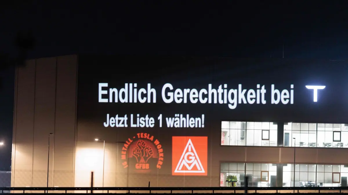 IG Metall Aktion bei Tesla: 26.02.2026, Brandenburg, Grünheide: Mitglieder der IG Metall beleuchten bei einer Protestaktion mit dem Slogan «Endlich Gerechtigkeit bei T. Jetzt Liste 1 wählen!» die Zellfabrik auf dem Werksgelände des Autobauers Tesla vor den bevorstehenden Betriebsratswahlen. Foto: Carsten Koall/dpa +++ dpa-Bildfunk +++