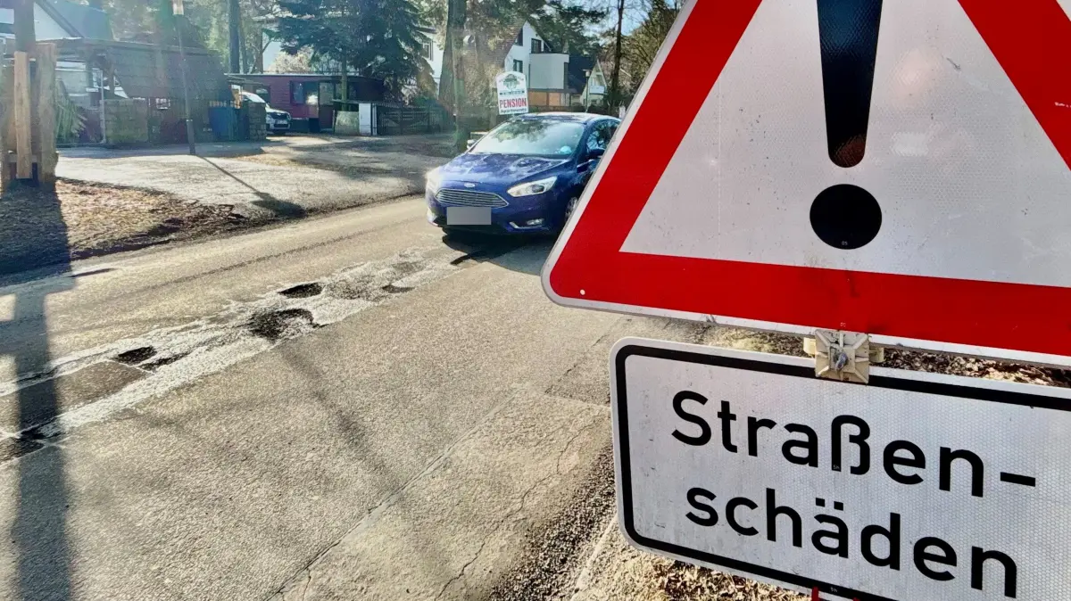 Schilder auf der Köpenicker Allee weisen auf Straßenschäden hin. Anwohner und Autofahrer fragen sich jedoch, was daran noch Straße sein soll.