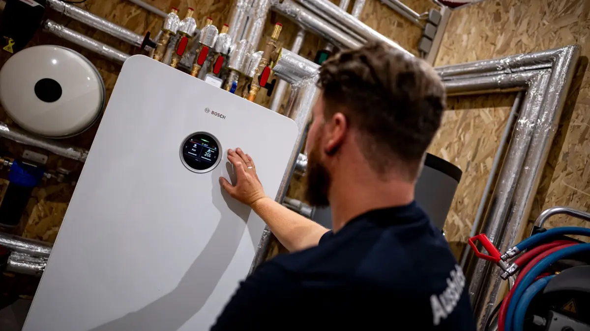 Handwerker zeigt an einer Wärmepumpe auf die Anzeige: ARCHIV - 14.06.2024, Brandenburg, Blankenfelde-Mahlow: Wer eine alte Gas- oder Ölheizung gegen eine moderne Alternative tauscht, kann noch immer von einer staatlichen Förderung profitieren. (zu dpa: «SPD will Mieter in neuem Heizungsgesetz schützen») Foto: Fabian Sommer/dpa/dpa-tmn +++ dpa-Bildfunk +++