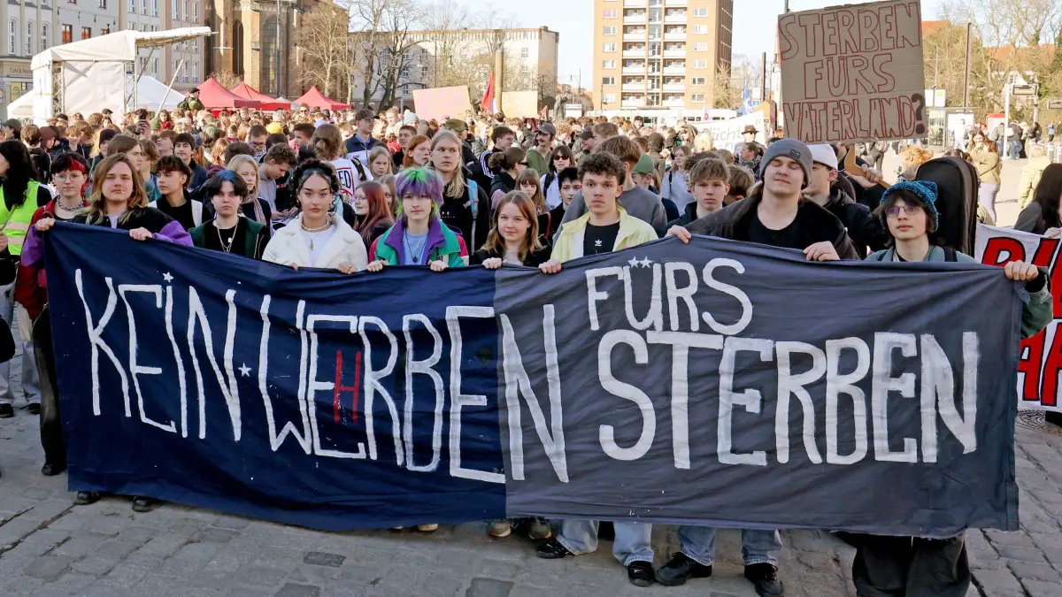 Bundesweiter Schulstreik gegen Wehrpflicht - Rostock: 05.03.2026, Mecklenburg-Vorpommern, Rostock: Auf dem Neuen Markt beginnt eine Demonstration gegen die Wehrpflicht, auf einem Transparent steht "Kein Werben fürs Sterben". Schüler, Eltern und Initiativen gehen beim bundesweiten Schulstreik gegen Wehrpflicht auf die Straße. Bereits am 5. Dezember 2025 hatten in vielen Städten Schülerinnen und Schüler gegen die Wehrdienst-Pläne der Bundesregierung demonstriert. Das Gesetz für den neuen Wehrdienst war am 1. Januar in Kraft getreten. (zu dpa: «Zehntausende Schüler protestieren gegen neuen Wehrdienst») Foto: Bernd Wüstneck/dpa +++ dpa-Bildfunk +++