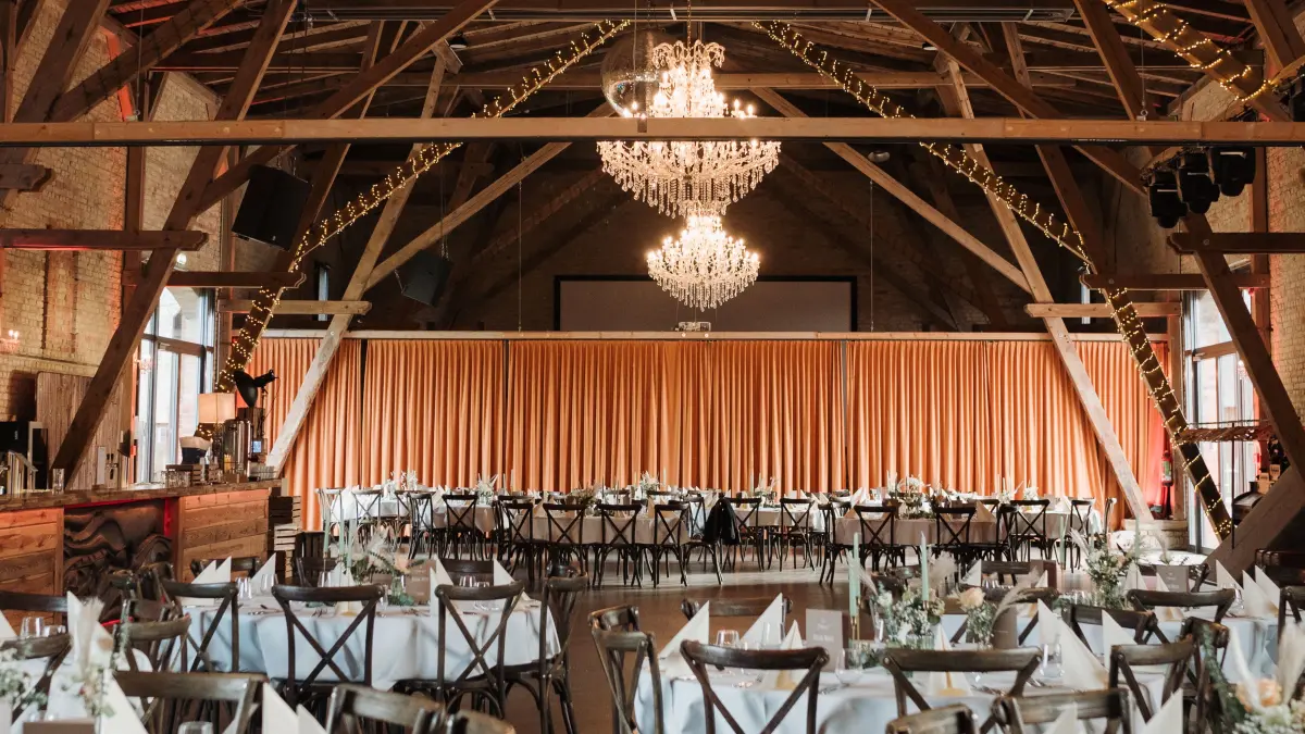 Warme Backsteinwände, ein Holzgebälk und strahlende Kronleuchtern bieten die perfekte Kulisse für eine Traumhochzeit