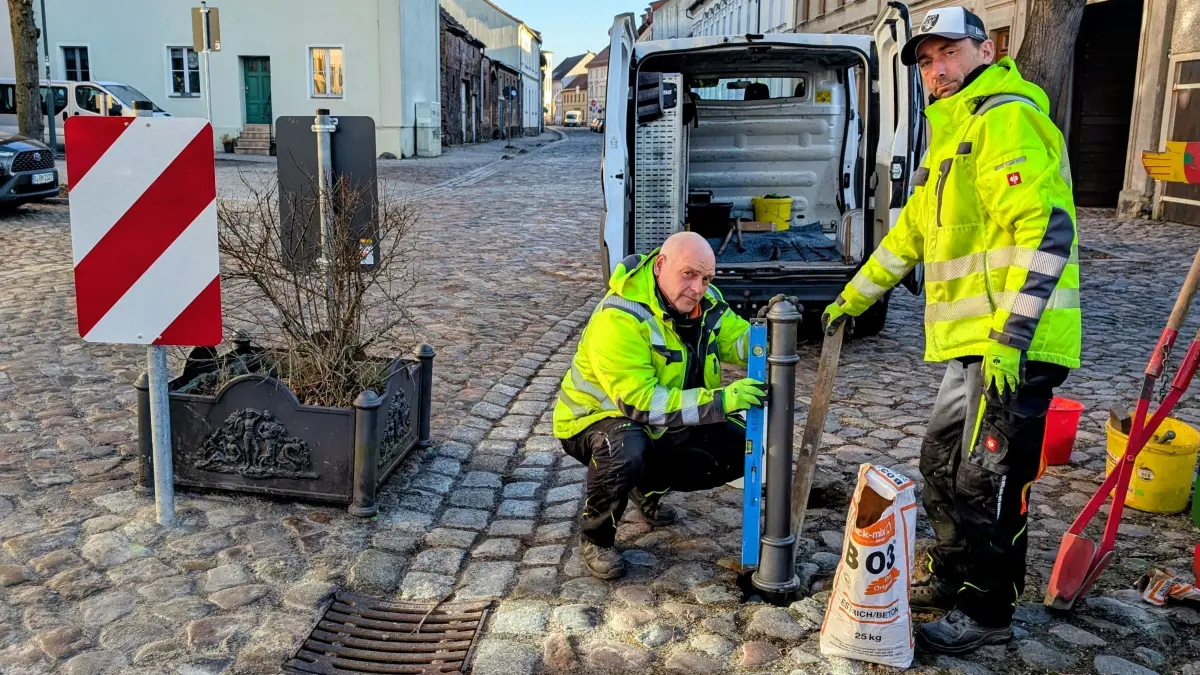 Altlandsberger Stadtarbeiter setzen einen Poller in der Klosterstraße. So soll der Bereich direkt an der Schule verkehrsberuhigt werden.