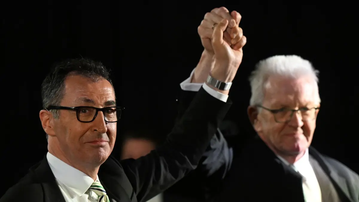 Landtagswahl in Baden-Württemberg - Bündnis 90/ Die Grünen: 08.03.2026, Baden-Württemberg, Stuttgart: Cem Özdemir (Bündnis 90/Die Grünen), Spitzenkandidat Landtagswahl Baden-Württemberg, und Winfried Kretschmann (Bündnis 90/Die Grünen), Ministerpräsident Baden-Württemberg, stehen bei der Wahlparty ihrer Partei nebeneinander und recken gemeinsam die Arme hoch. Am 8. März fand in Baden-Württemberg die Landtagswahl statt. Foto: Bernd Weißbrod/dpa +++ dpa-Bildfunk +++