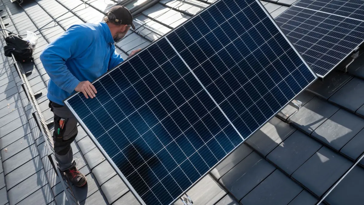 Montage von Photovoltaik-Modulen: ARCHIV - 13.10.2021, Baden-Württemberg, Stuttgart: Mitarbeiter einer Solar-Firma montieren Photovoltaikmodule auf dem Dach eines Wohnhauses. (zu dpa: «Grüne: Energiewende wichtig für Unabhängigkeit») Foto: Marijan Murat/dpa +++ dpa-Bildfunk +++