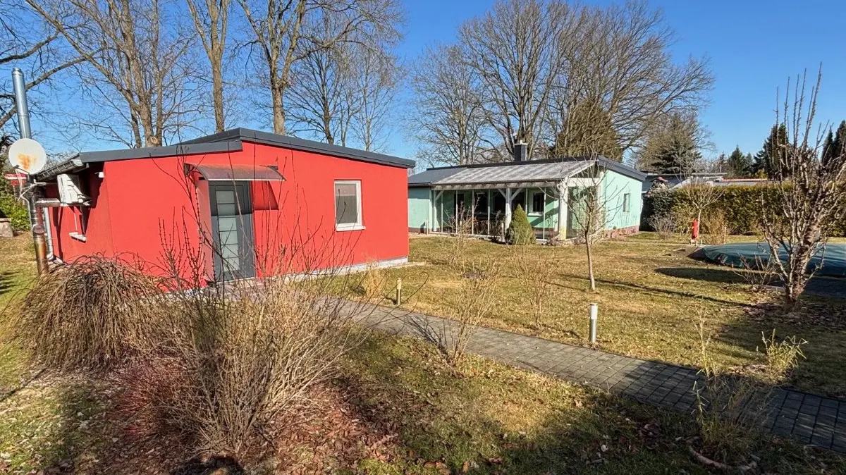 Rot und grün - zwei Bungalows werden in Neuruppin zum Kauf angeboten. Darin die Eltern und der Sohn mit Familie gelebt. Jetzt wird das große Grundstück vermarktet. So sehen die Gründe dafür und dagegen aus.