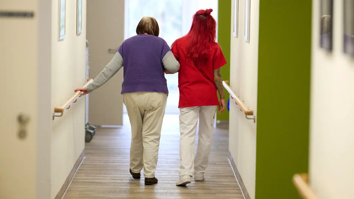 Pflege: ARCHIV - 12.03.2025, Nordrhein-Westfalen, Essen: Eine Pflegekraft begleitet in einem Pflegezentrum eine Seniorin durch den Flur. (zu dpa: «Wo bleibt Sachsen-Anhalts Pflegeplatzfinder?») Foto: Bernd Thissen/dpa +++ dpa-Bildfunk +++
