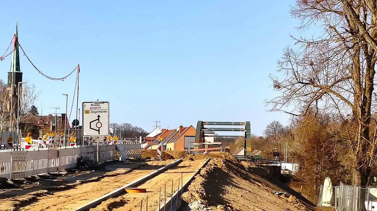 Die Brückenbaustelle im März 2026. Arbeiten an der Böschung sind zu erkennen. Die neue Brücke selbst liegt jedoch weiterhin statt auf den Brückenpfeilern vor der Sparkasse.