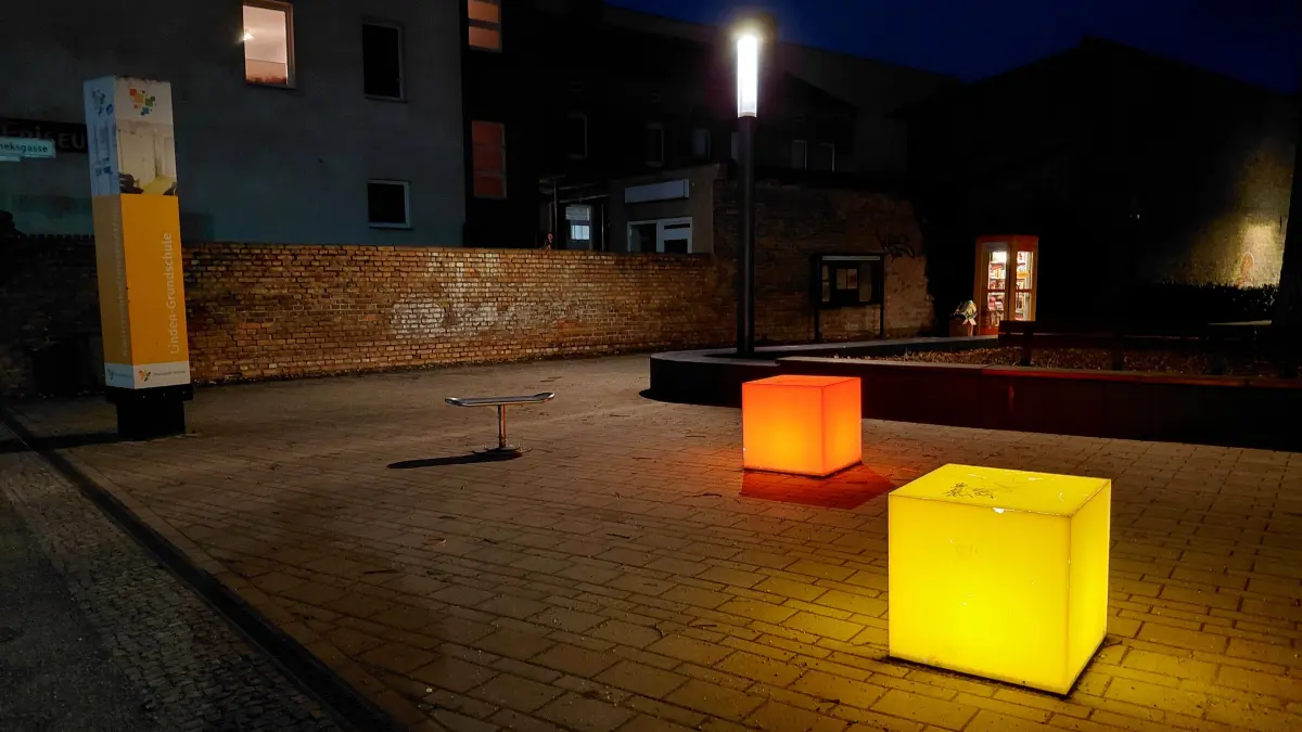 Ofenstadt Velten, Platz vor Kommunikationszentrum und Stadtbibliothek bei Nacht, Lichthocker