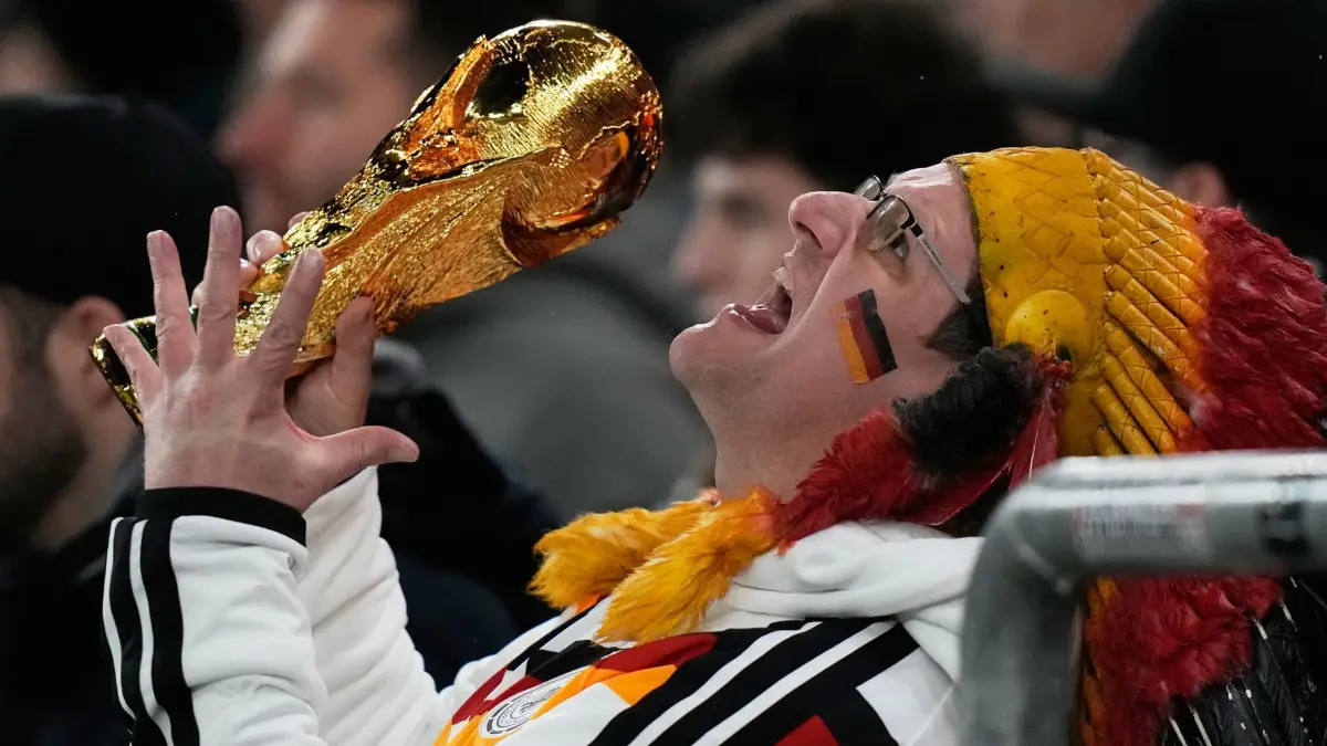 Deutschland - Ghana: 30.03.2026, Baden-Württemberg, Stuttgart: Fußball, Männer, Länderspiele, Deutschland - Ghana, MHP Arena. Ein deutscher Fan reagiert auf der Tribüne mit einer Kopie des WM-Pokals. Foto: Matthias Schrader/AP/dpa - WICHTIGER HINWEIS: Gemäß den Vorgaben der DFL Deutsche Fußball Liga bzw. des DFB Deutscher Fußball-Bund ist es untersagt, in dem Stadion und/oder vom Spiel angefertigte Fotoaufnahmen in Form von Sequenzbildern und/oder videoähnlichen Fotostrecken zu verwerten bzw. verwerten zu lassen. +++ dpa-Bildfunk +++