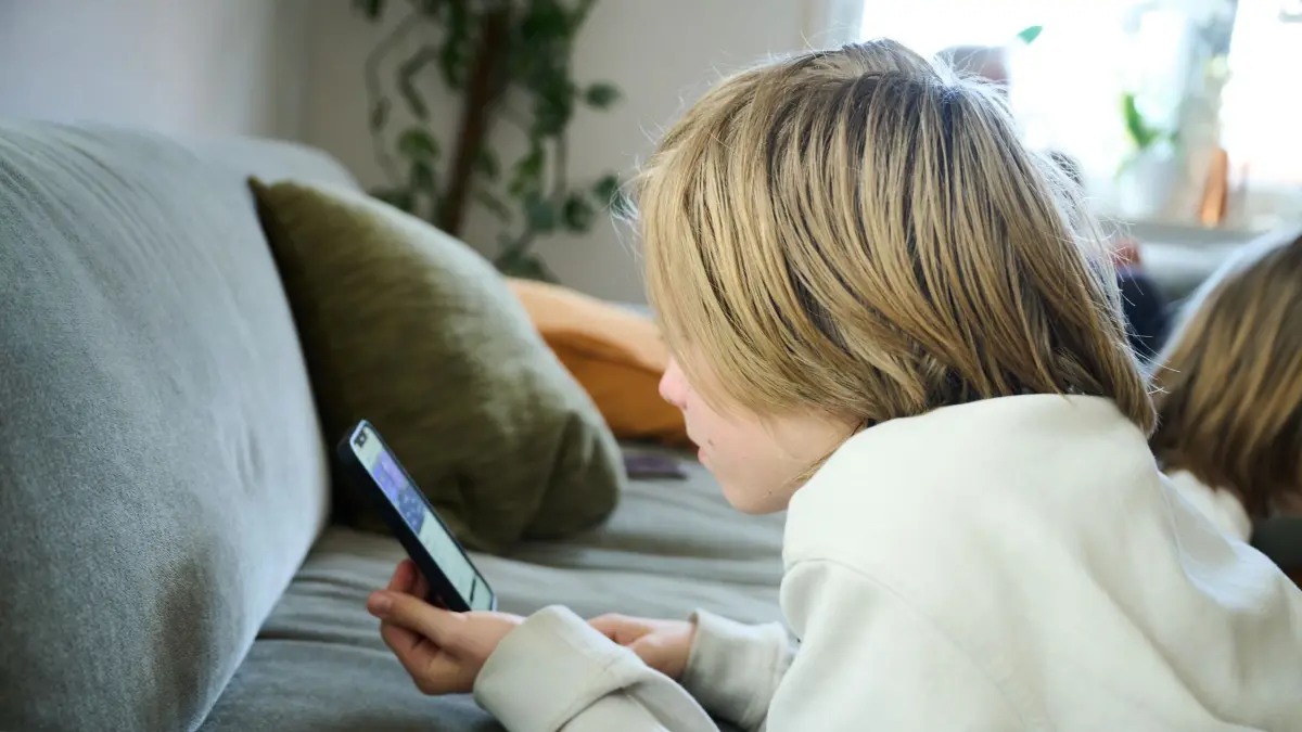 Handynutzung Kinder: ARCHIV - 21.04.2025, Bayern, Roth: ILLUSTRATION - Ein Junge liegt auf einem Sofa und guckt auf sein Smartphone. (gestellte Szene) (zu dpa: «Frankreichs Senat berät zu Social-Media-Verbot unter 15») Foto: Annette Riedl/dpa +++ dpa-Bildfunk +++