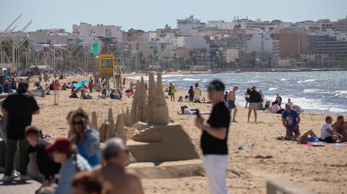 Strandtag auf Mallorca: 04.04.2026, Spanien, Palma: Menschen sonnen sich am Strand Playa de Palma auf Mallorca während der Feierlichkeiten zur Karwoche. Foto: Clara Margais/dpa +++ dpa-Bildfunk +++