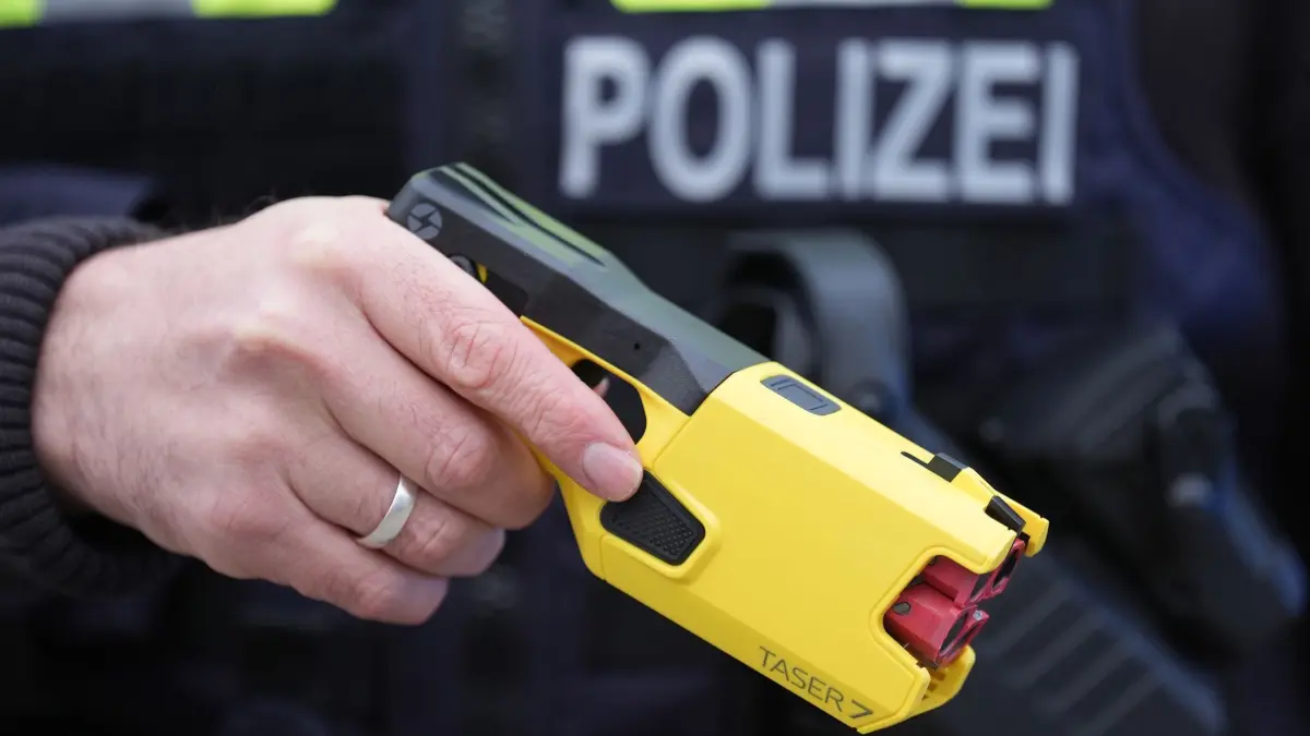Distanzelektroimpulsgerät: ARCHIV - 11.12.2024, Schleswig-Holstein, Kiel: ILLUSTRATION - Ein Polizist hält das Distanz-Elektroimpulsgerät „Taser 7“ auf dem Gelände des Polizeizentrums Eichhof in der Hand. (zu dpa: «Mit Elektroschocker: Polizei nimmt Betrunkenen fest») Foto: Marcus Brandt/dpa +++ dpa-Bildfunk +++
