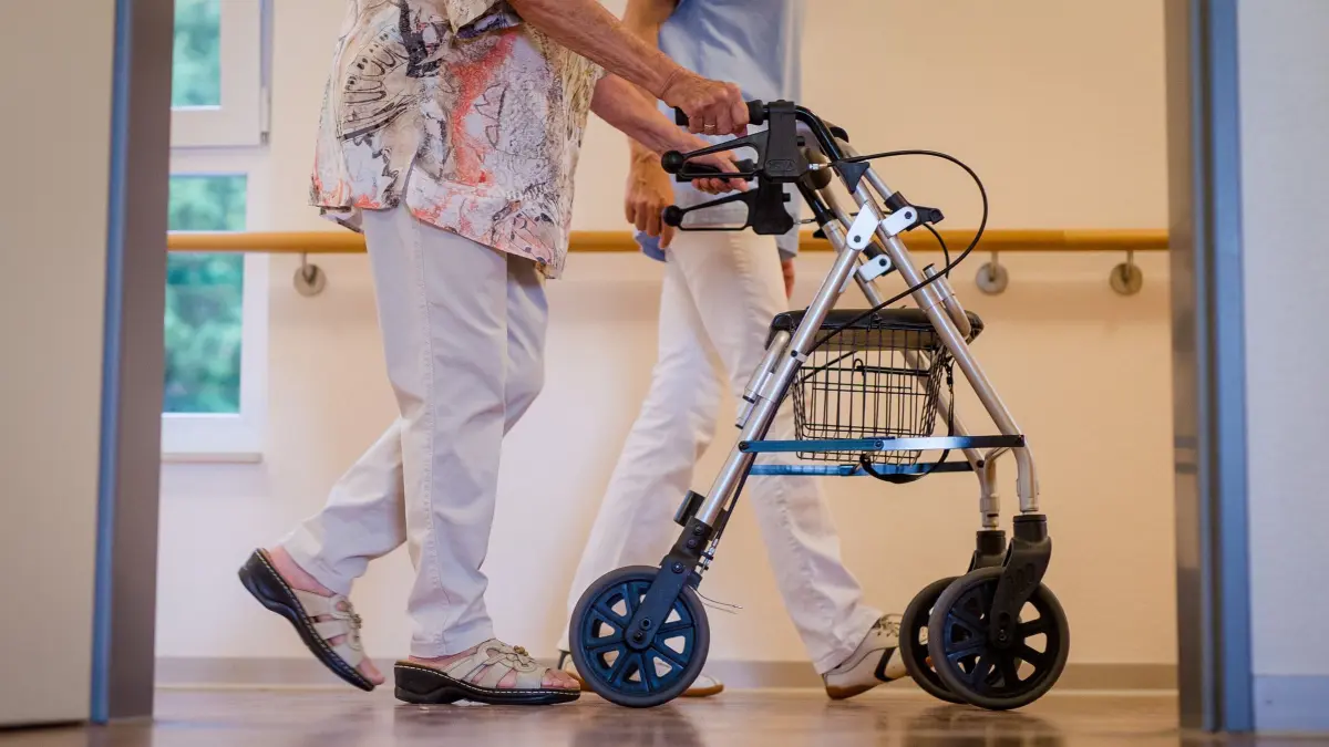 Pflegeheim: ARCHIV - 23.08.2018, Baden-Württemberg, Stuttgart: Eine Pflegekraft geht in einem Pflegeheim mit einer älteren Dame über einen Korridor. (zu dpa: «Keine Schließung: Pflege in Seniorenheim in Unna gesichert») Foto: Christoph Schmidt/dpa +++ dpa-Bildfunk +++