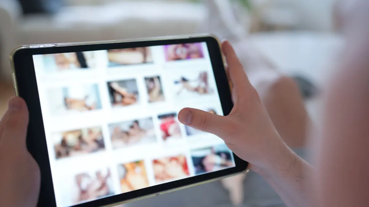 Pornografie im Internet: ARCHIV - 14.04.2025, Hamburg: Ein junger Mann schaut sich auf einem Smartphone eine Porno-Internetseite an (gestellte Szene). (zu dpa: «Deepfake-Pornos: Ermittler in Hessen stoßen an ihre Grenzen») Foto: Marcus Brandt/dpa +++ dpa-Bildfunk +++