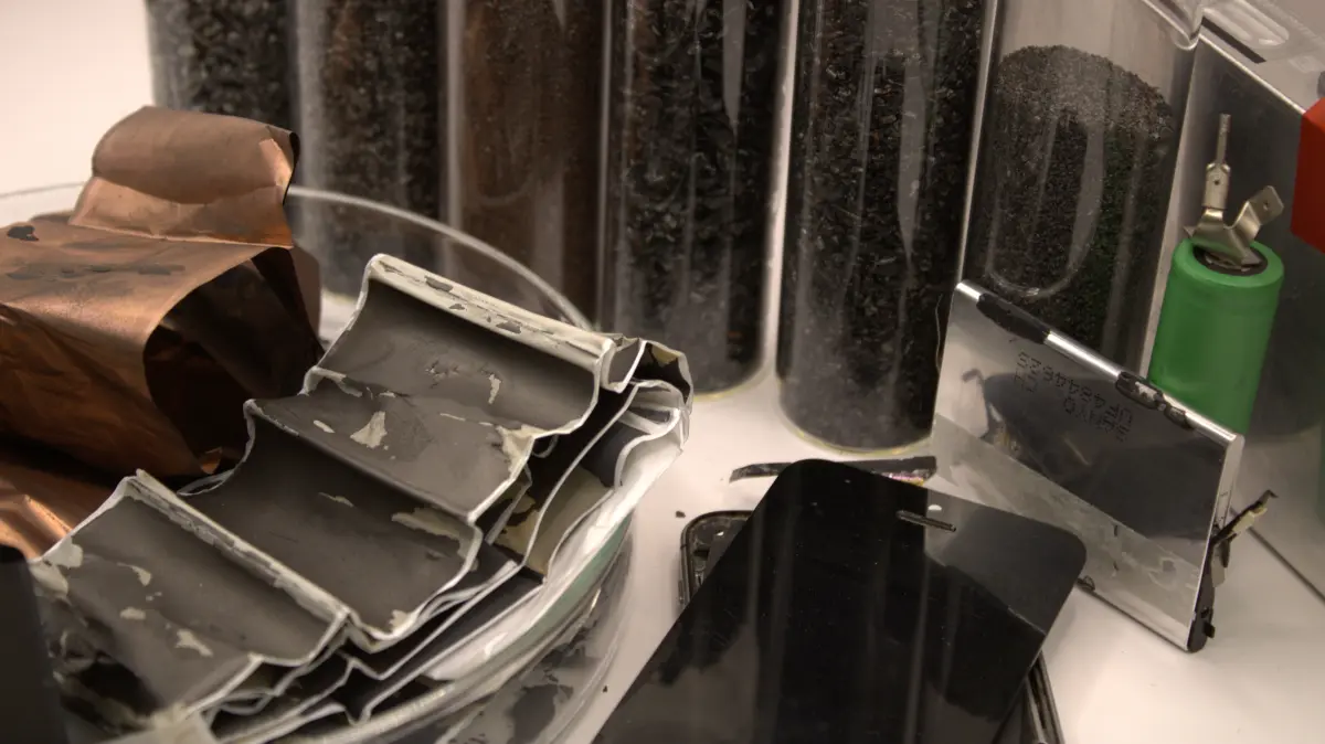 Vom Handy bis zur Traktionsbatterie – Lithium-Ionen-Zellen aus unterschiedlichen Anwendungen im Vordergrund. Im Hintergrund ein Blick ins Innere: Elektroden, Separatoren und Materialfraktionen aus dem Recyclingprozess.