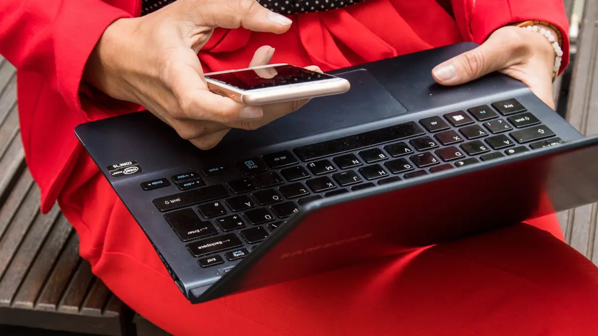 Eine Frau hält ein Smartphone und ein Laptop in den Händen: ILLUSTRATION - Ungewöhnliche Aktivitäten im Postfach: Auffällige Anmeldeversuche oder fremde Nachrichten deuten auf einen möglichen Hackerangriff hin. (zu dpa: «E-Mail-Konto gehackt: Was Sie jetzt tun sollten») Foto: Christin Klose/dpa-tmn - Honorarfrei nur für Bezieher des dpa-Themendienstes +++ dpa-Themendienst +++