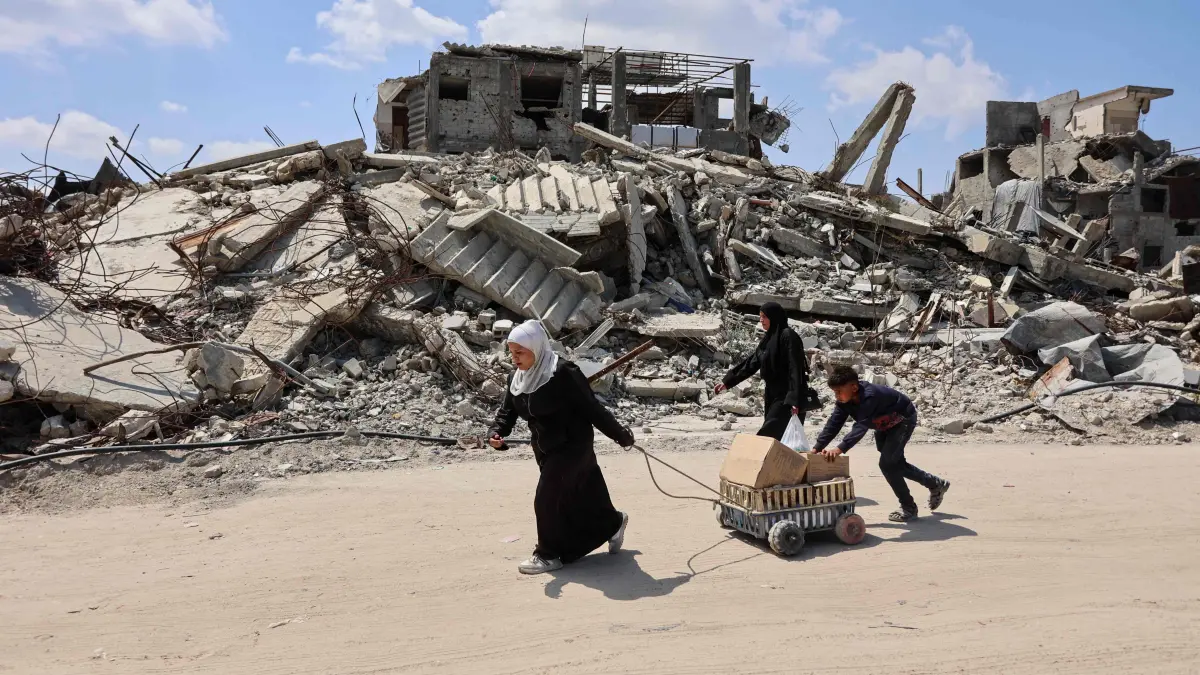 Displaced Palestinians carry boxes in a cart past the rubble of destroyed buildings at the Jabalia refugee camp in the northern Gaza Strip on April 13, 2026. Since the terms of a US-brokered ceasefire deal came into effect on October 10, Israel remains in control of nearly half of the Gaza Strip, including all its border areas. Nearly two million people in Gaza are living in makeshift shelters, and the humanitarian situation remains dire, according to aid agencies. (Photo by Omar AL-QATTAA / AFP)