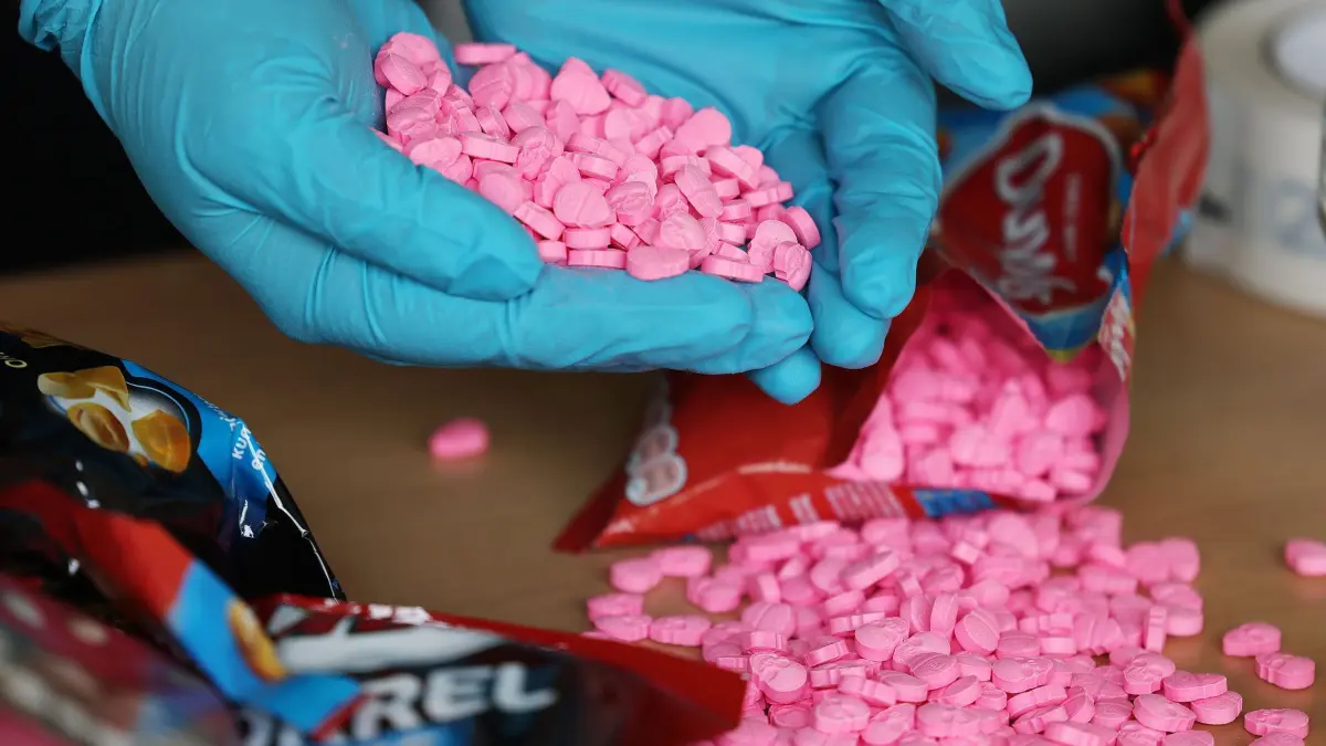 Drogen: ARCHIV - 15.06.2021, Nordrhein-Westfalen, Köln: Ein Zollbeamter hält Ecstasy Tabletten in der Hand, die sichergestellt wurden (Symbolbild). (zu dpa: «Drogen an Kinder verkauft - Mutmaßliches Drogennetz entdeckt») Foto: Oliver Berg/dpa +++ dpa-Bildfunk +++