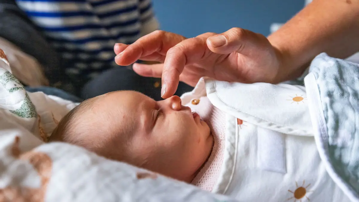So wenige Geburten wie seit 1946 nicht mehr: Eine Hebamme streicht ueber das Gesicht eines 14 Tage alten Saeuglings (Themenfoto vom 17.08.2023). Rund 654.300 Kinder wurden im vergangenen Jahr in Deutschland geboren, so wenige waren es letztmals in der unmittelbaren Nachkriegszeit. Im Osten ist der Rueckgang besonders stark. Mehr Neugeborene als im Jahr zuvor gibt es nur in Hamburg. (Siehe epd-Meldung vom 28.04.2026)