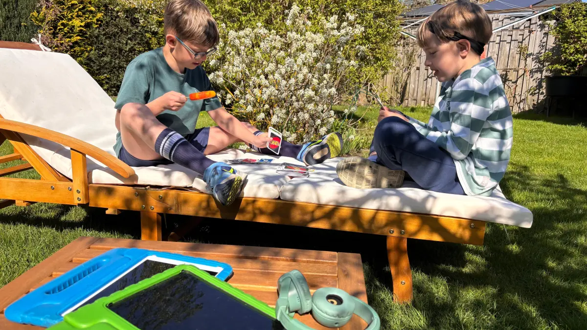 Karten statt Tablet: Benjamin und Henri genießen einen Spielenachmittag im Garten, während die Tablets ungenutzt auf dem Tisch liegen. In der Familie gehören digitale Geräte zum Alltag, bestimmen ihn aber nicht immer.