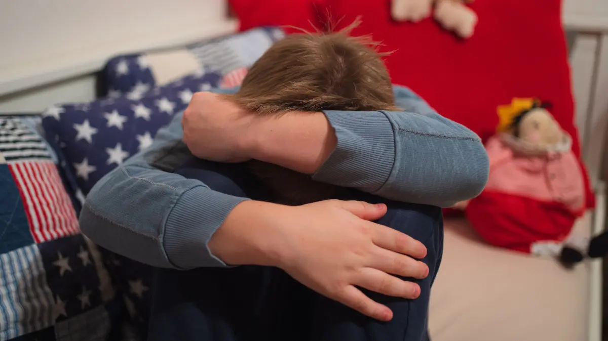 Ein Junge kauert sich auf seinem Bett zusammen. Aufsichtspersonen in Vereinen oder Kirchen können bisher nur strafrechtlich belangt werden, wenn sie sexuellen Missbrauch von Kindern absichtlich ermöglichen. Bayerns Justizminister fordert deshalb schärfere Regeln. (zu dpa: «Bayern fordert Strafen bei fahrlässigem Umgang mit Kindesmissbrauch») +++ dpa-Bildfunk +++