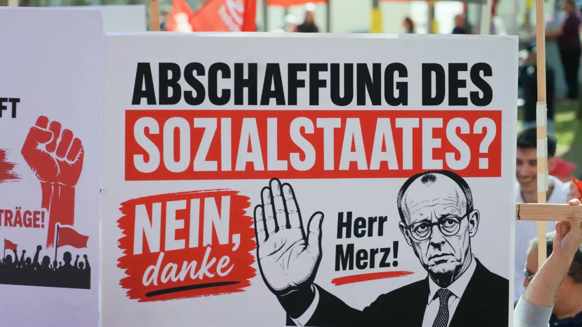 DGB-Kundgebung zum Tag der Arbeit - Herborn: 01.05.2026, Hessen, Herborn: Ein Demonstrationsplakat mit der Aufschrift «Abschaffung des Sozialstaates? Nein, danke Herr Merz!» ist zu sehen, bei der Hauptkundgebung DGB Hessen-Thüringen u.a. mit dem hessischen DGB-Vorsitzenden Rudolph und Landeswirtschaftsminister Mansoori (SPD) im Stadtpark. Anlass sind bundesweite Kundgebungen der Gewerkschaften zum internationalen Tag der Arbeit. Foto: Sascha Ditscher/dpa +++ dpa-Bildfunk +++