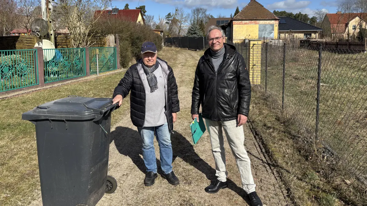 Gesperrte Straße: Arno Henning (l.), Anwohner der Alten Bahnhofstraße in Bralitz, und Ortsvorsteher Rainer Texdorf. Seine Mülltonne müsste Henning eine Kilometer weit zum Abstellort ziehen. Ein Bauzaun am alten Bahnhof im Hintergrund versperrt die Straße.