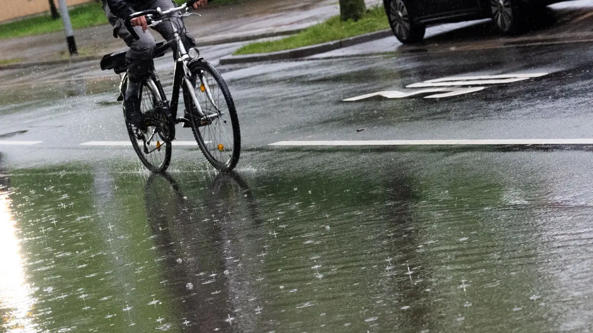 Regen in Niedersachsen: 06.05.2026, Niedersachsen, Hannover: Ein Fahrradfahrer fährt auf einer Straße, auf der sich Regenwasser gestaut hat. Der Deutsche Wetterdienst sagt schauerartige Regenfälle und gebietsweise Starkregen mit größeren Regenmengen voraus. Foto: Julian Stratenschulte/dpa +++ dpa-Bildfunk +++