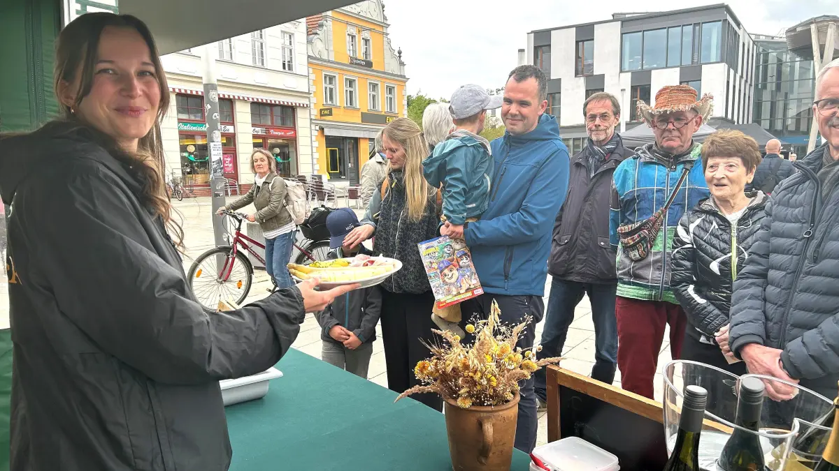 Spargelzeit in Eberswalde: Denise Schilling vom Restaurant der Kochkommode reicht auf dem Marktplatz den nächsten Teller mit dem Edelgemüse, Kartoffeln, Schinken und Sauce hollandaise an die wartende Kundschaft weiter.