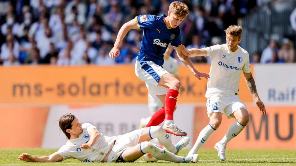 Holstein Kiel - 1. FC Magdeburg: 09.05.2026, Schleswig-Holstein, Kiel: Fußball, Männer: 2. Bundesliga, Holstein Kiel - 1. FC Magdeburg, 33. Spieltag, Holstein-Stadion. Jean Hugonet (l, 1. FC Magdeburg), Phil Harres (Holstein Kiel, M) und Marcus Mathisen (1. FC Magdeburg) kämpfen um den Ball. Foto: Philipp Szyza/dpa +++ dpa-Bildfunk +++