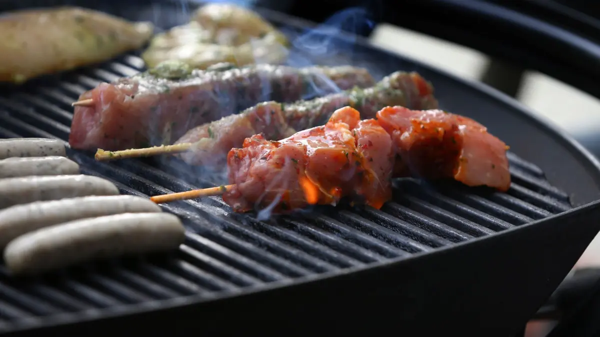 Grillen: ARCHIV - 26.05.2018, Bayern, München: Fleischspieße, Bratwürste und Steaks liegen auf dem Rost eines Gasgrills. (zu dpa: «Grill brennt bei Firmenfeier - ein Verletzter») Foto: Karl-Josef Hildenbrand/dpa +++ dpa-Bildfunk +++