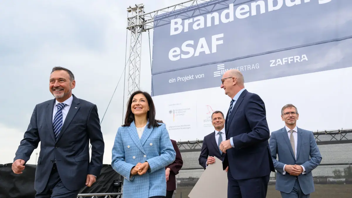Raffinerie PCK: 11.05.2026, Brandenburg, Schwedt/Oder: Ralf Schairer (l-r), Geschäftsführer der Raffinerie PCK, Katherina Reiche (CDU), Bundeswirtschaftsministerin, Jan Toschka, CEO von Zafra, Dietmar Woidke (SPD), Ministerpräsident von Brandenburg und Gunar Hering, CEO von Enertrag nehmen an der Übergabe eines Fördermittelbescheides von rund 350 Millionen Euro für das Projekt "Brandenburg eSAF" auf dem Gelände der Raffinerie PCK teil. Auf dem Gelände der Raffinerie in Schwedt soll die in Deutschland größte Anlage zur Produktion von nachhaltigen Flugkraftstoffen entstehen. Foto: Patrick Pleul/dpa +++ dpa-Bildfunk +++