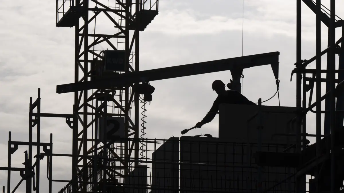 Ein Bauarbeiter arbeitet auf einer Baustelle (Symbolbild). In Wriezen wird darüber gestritten, wie die Stadt einheimische Unternehmen bei der Auftragsvergabe mehr berücksichtigen kann.