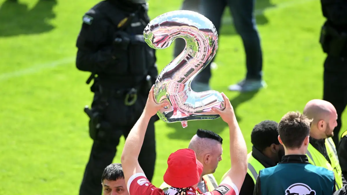 Jahn Regensburg - Energie Cottbus: 16.05.2026, Bayern, Regensburg: Fußball, Männer: 3. Liga, Jahn Regensburg - Energie Cottbus, 38. Spieltag, Jahnstadion Regensburg. Ein Cottbuser Fan habt eine 2 für den Aufstieg in die 2. Bundesliga in die Höhe. WICHTIGER HINWEIS: Gemäß den Vorgaben der DFL Deutsche Fußball Liga bzw. des DFB Deutscher Fußball-Bund ist es untersagt, in dem Stadion und/oder vom Spiel angefertigte Fotoaufnahmen in Form von Sequenzbildern und/oder videoähnlichen Fotostrecken zu verwerten bzw. verwerten zu lassen. Foto: Jens Niering/dpa +++ dpa-Bildfunk +++
