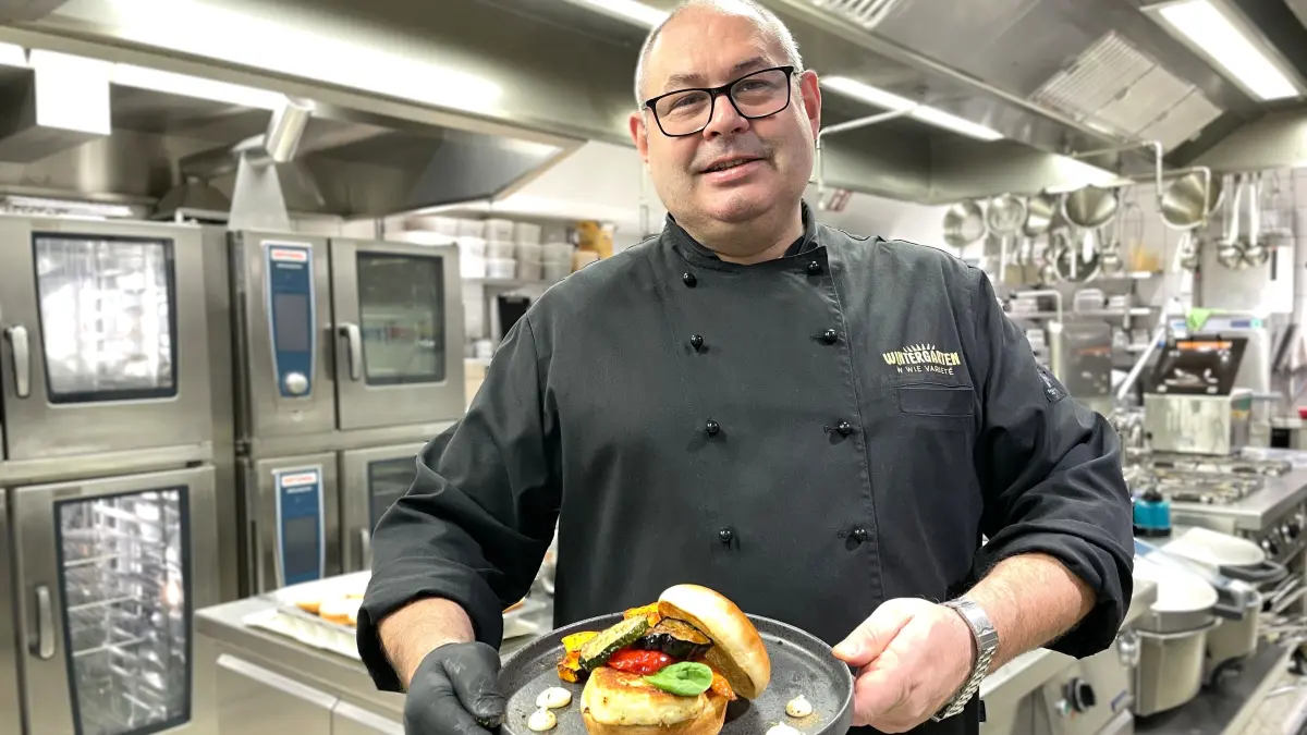 Der Küchenchef des Varieté Wintergarten, Thomas Figovic, hält am 28.04.2026 einen vegetarischen Burger in seiner Küche.