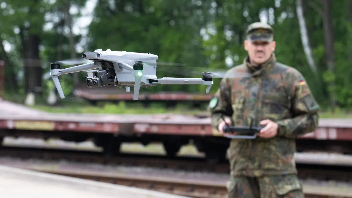 Erste Großübung der Heimatschutzdivision: 20.05.2026, Niedersachsen, Bergen: Ein Heimatschützer der Heimatschutzdivision steuert eine Drohne während einer Übung am Truppenübungsplatz bei der Bahnentladung von Kettenfahrzeugen der Panzergrenadierbrigade 37. Mehr als 600 Soldatinnen und Soldaten der Heimatschutzdivision üben in diesen Tagen die Funktionsfähigkeit der Drehscheibe Deutschland. Drei Wochen lang wird an mehreren Standorten in Bayern, Hessen und Niedersachsen unter dem Titel Vigilant Roland I geübt. Foto: Julian Stratenschulte/dpa +++ dpa-Bildfunk +++