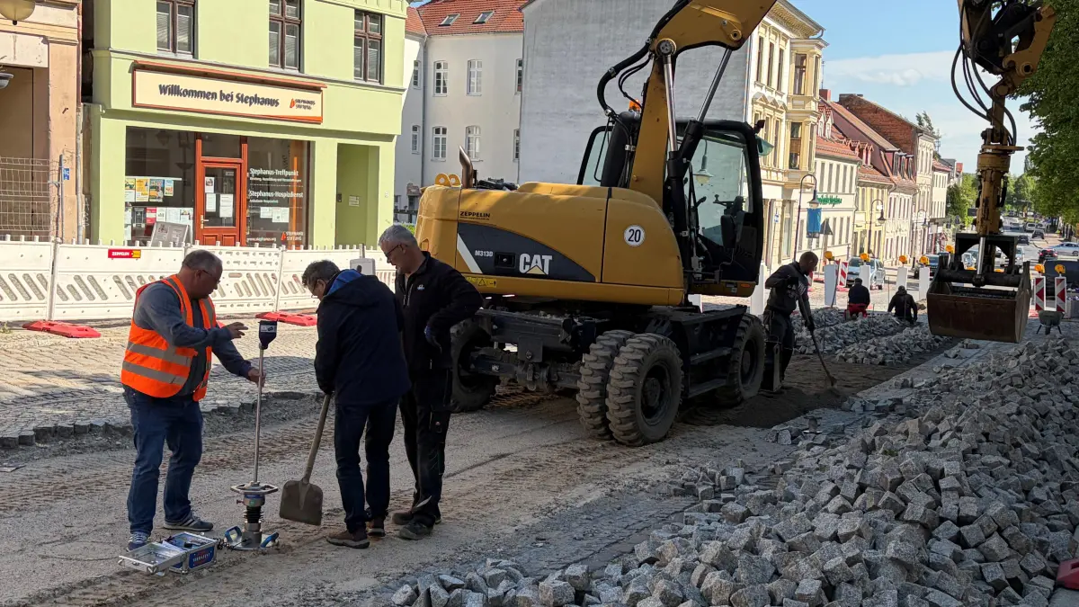 Baustelle in Bad Freienwalde: Bauleiter Matthias Mosebach, GUT-Bau-Geschäftsführer Burkhard Kautschmann und Vorarbeiter Thomas Pawloski messen die Verdichtung des Unterbaus der Natursteinpflasterstraße. Wann ist dort wieder freie Fahrt?