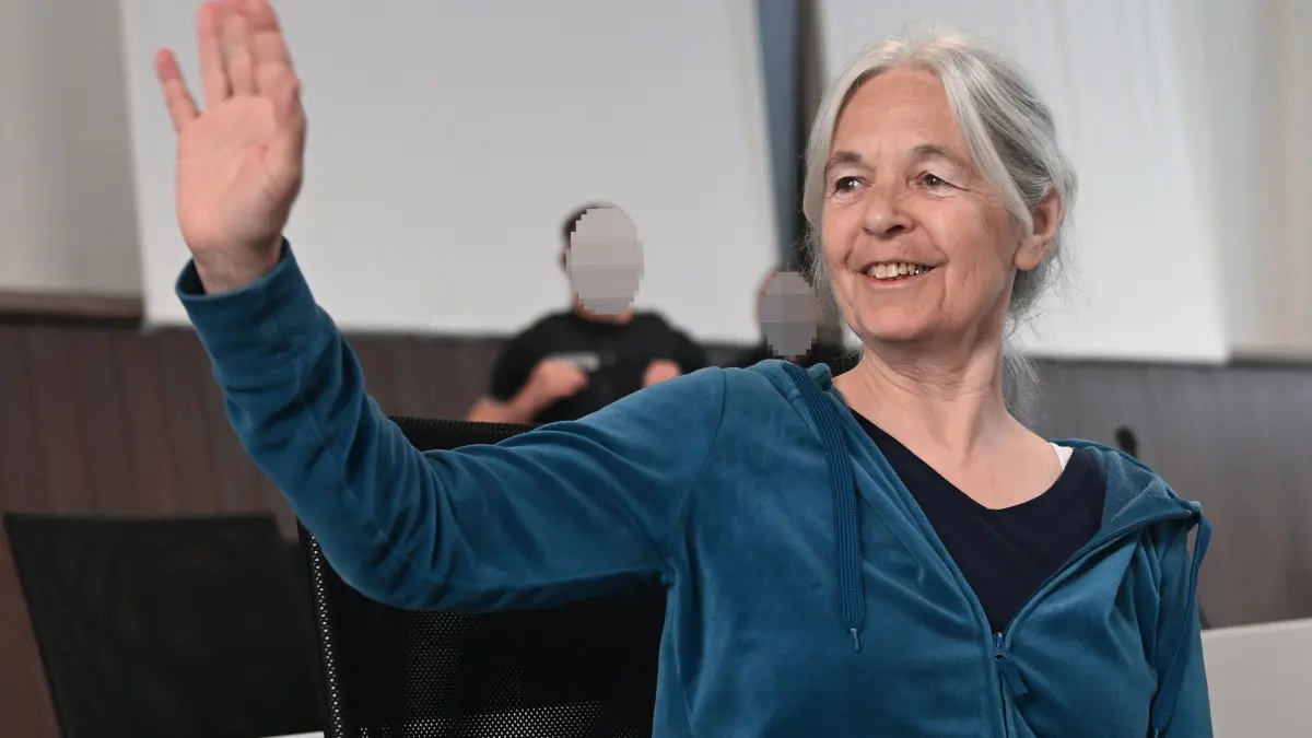 Daniela Klette, former member of German far-left militant group The Red Army Faction (RAF) waves in the courtroom of the Verden Regional Court for a continuation of the trial against her on May 27, 2026 in Verden, northern Germany. Daniela Klette is a former member of Germany's far-left Baader-Meinhof gang, a radical anti-capitalist group that carried out a series of killings, bombings and kidnappings mainly in the 1970s and 1980s. Klette was arrested at an apartment in Berlin's bohemian Kreuzberg neighbourhood in February 2024 after evading the authorities for more than 30 years. (Photo by Sina Schuldt / POOL / AFP) / ALTERNATIVE CROP